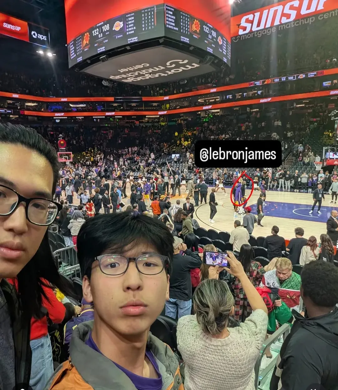 Ian and a friend at an NBA game, with LeBron James circled far down on the court
