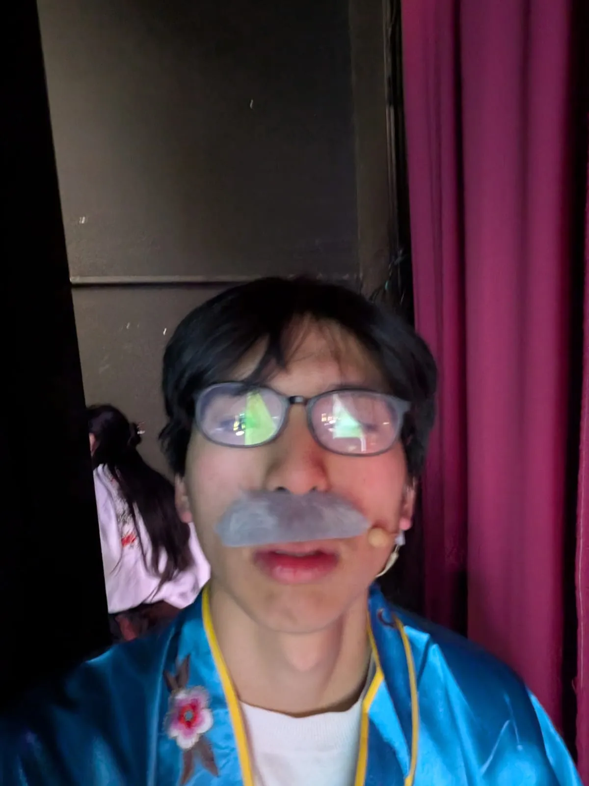 Ian in a blue robe costume with a false white moustache