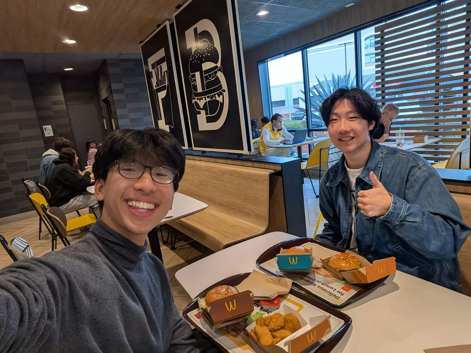 Ian and a friend with trays of food at a McDonald’s