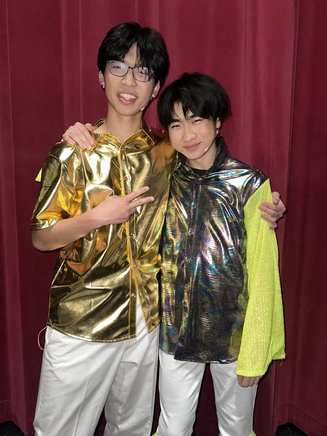 Ian and a castmate in metallic gold and iridescent costumes in front of a red curtain